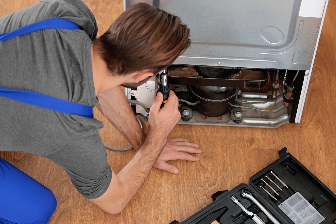 Male Technician Repairing Refrigerator Indoors